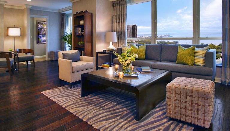 Wohnzimmer der Suite mit Sofa, Tisch und großen Fenstern mit herrlichem Ausblick