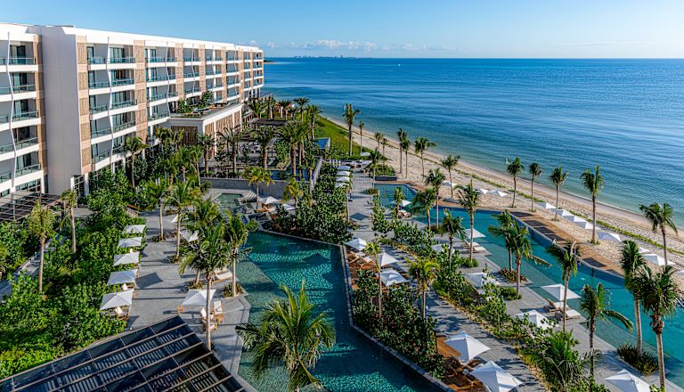 Exterior of hotel building, outdoor pools and nearby beach