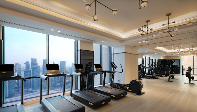 Máy chạy bộ trong trung tâm thể dục với chế độ xem thành phố từ cửa sổ lớn