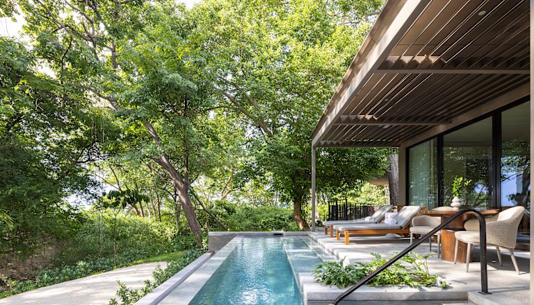 Patio privado de la suite Pacifico bajo los árboles, piscina profunda, divanes