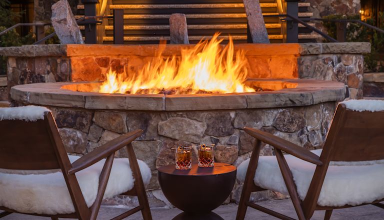 Two Cocktail Glasses on a  Small Table by a Fire Pit