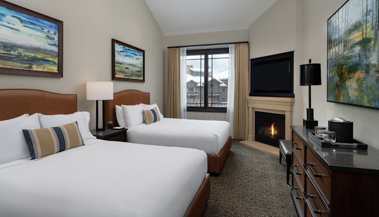 2 beds in room with TV and fireplace