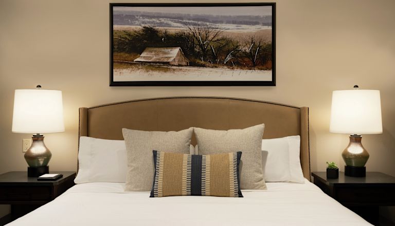Bed in room with art on wall and lamps