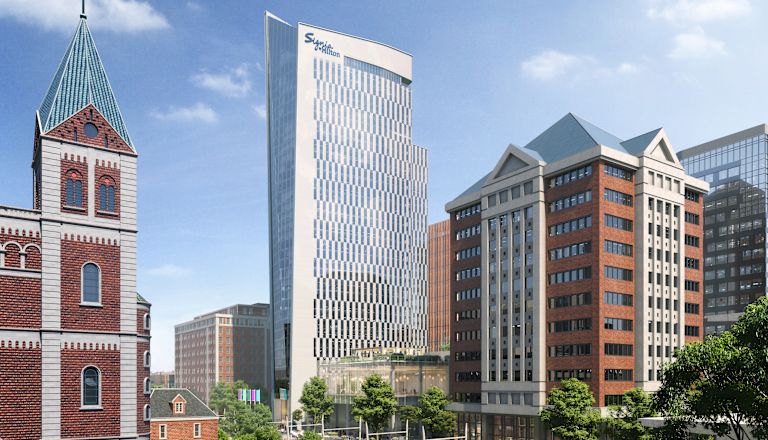 Exteriér hotelu obklopený stromy a budovami