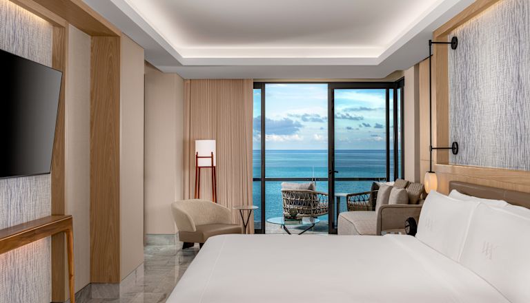 King bedroom with wall mounted TV, sofa and balcony access