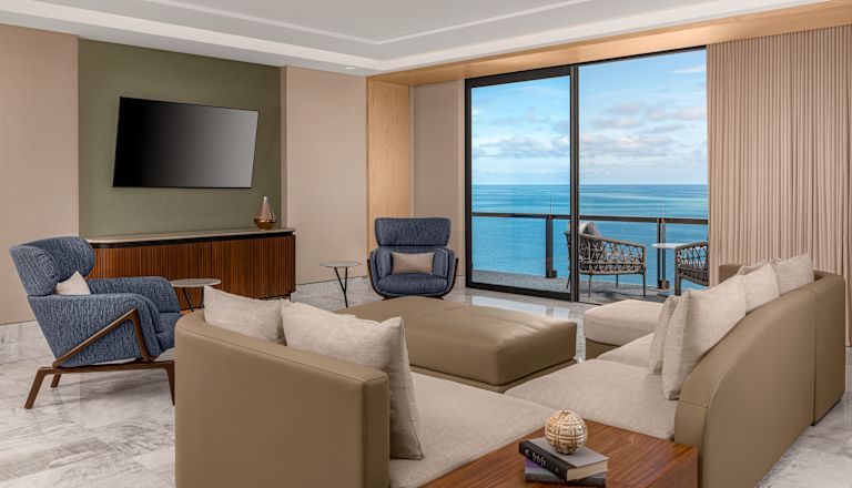 Suite living room with sofa, chairs,balcony access and wall mounted TV