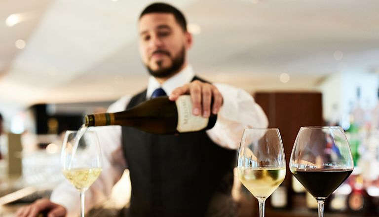 ساعة التخفيضات في مطعم وبار أتريو واين، وساقي يصب النبيذ