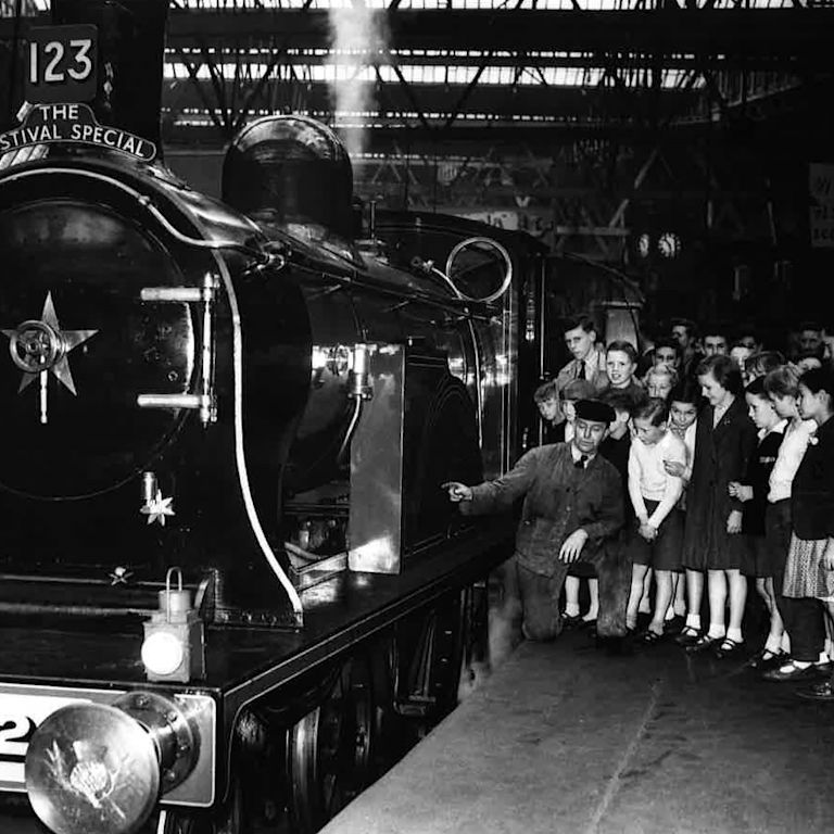 Old shot of station staff showing people train