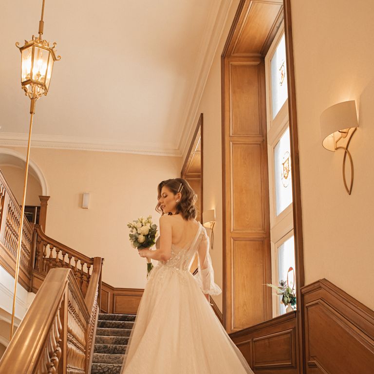Bride Standing on a Staircase, Holding a Bouquet of White Flowers