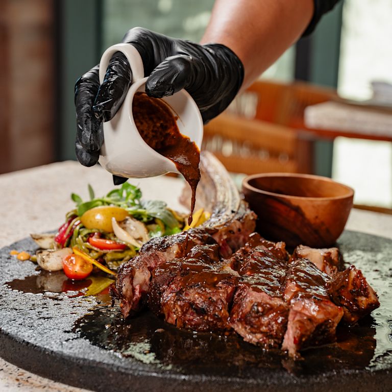 Maxal 餐廳的主廚將醬料加到碟子上，配以肉類