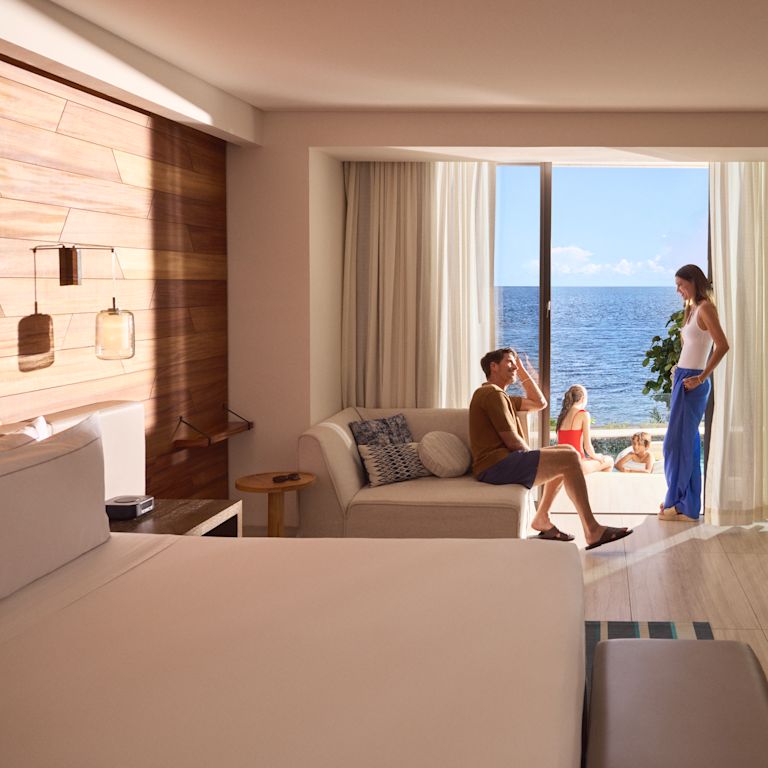 Anne ve baba, kız ve oğul dışarıda dinlenirken modern bir denize sıfır otel odasında dinlenip konuşurken