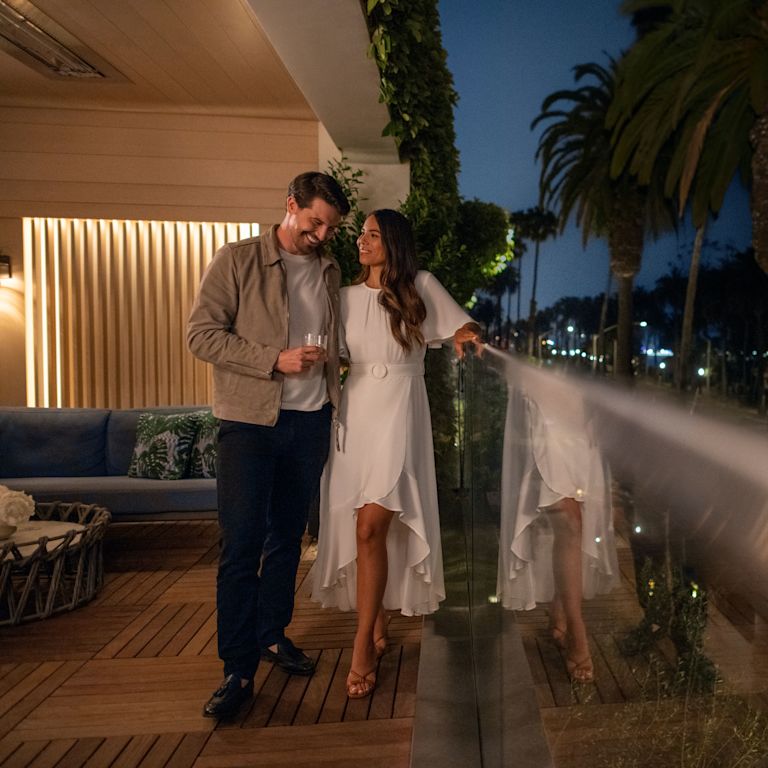 Casal na varanda do terraço ao pôr do sol