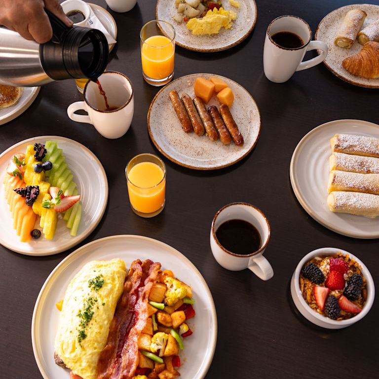 Waiter serving coffee in a table setup with breakfast foods