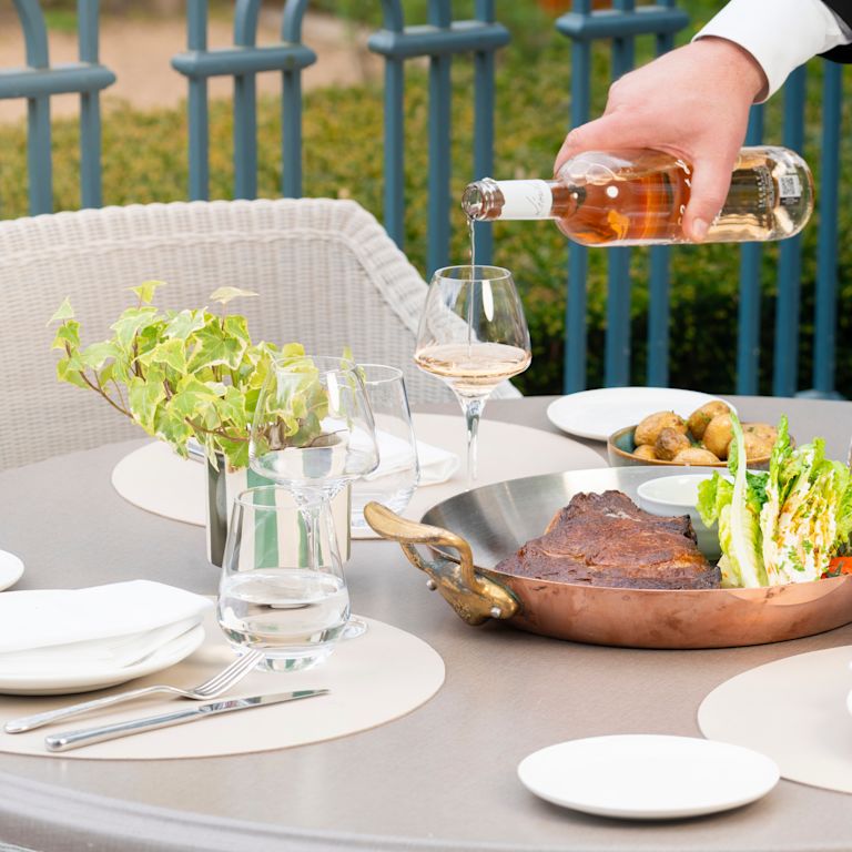Un uomo che versa il vino in un bicchiere mentre cena al ristorante La Veranda