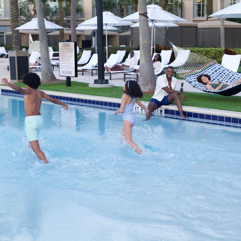 huéspedes descansando junto a la piscina, niños jugando en la piscina