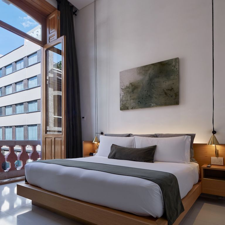 Camera con letto e doppie porte aperte sul balcone.