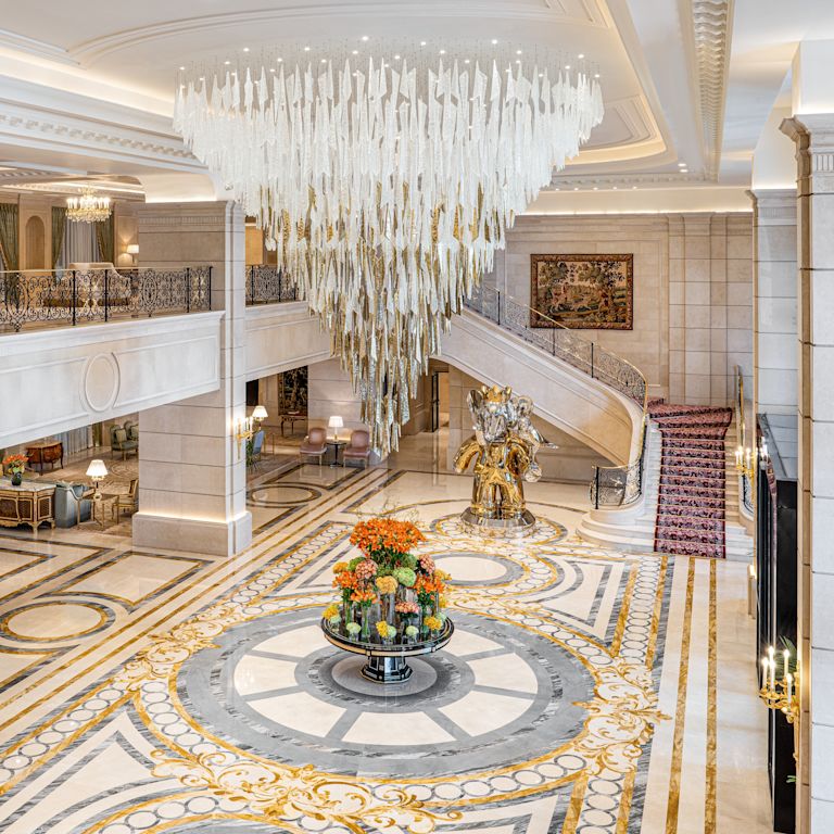 Lobby con fiori, scale che conducono a una mezzanino e un grande lampadario