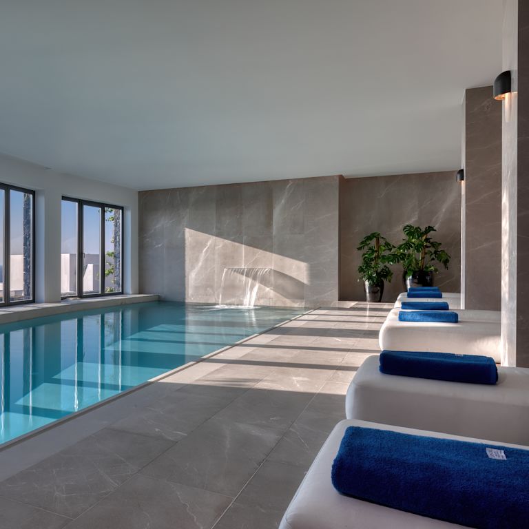 Pool in spa with soft loungers and a waterfall.
