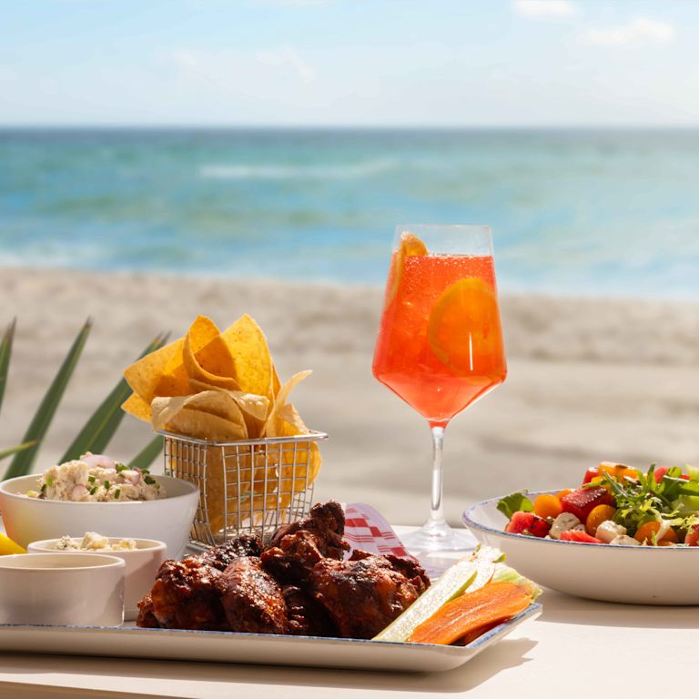 Mâncare și băuturi pe masă la restaurantul Playa de pe plajă