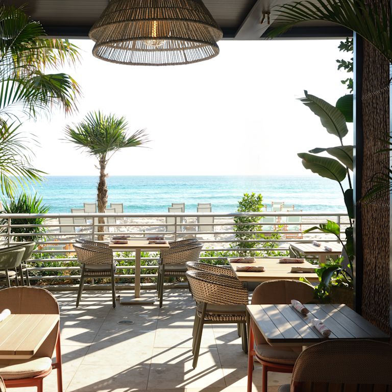 Zonă de luat masa pe terasa Playa Beach Bar and Grill cu vedere spre plajă