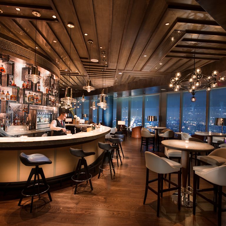 Sip Wine bar with high-top tables, chairs, and windows with outdoor view, lit up at night