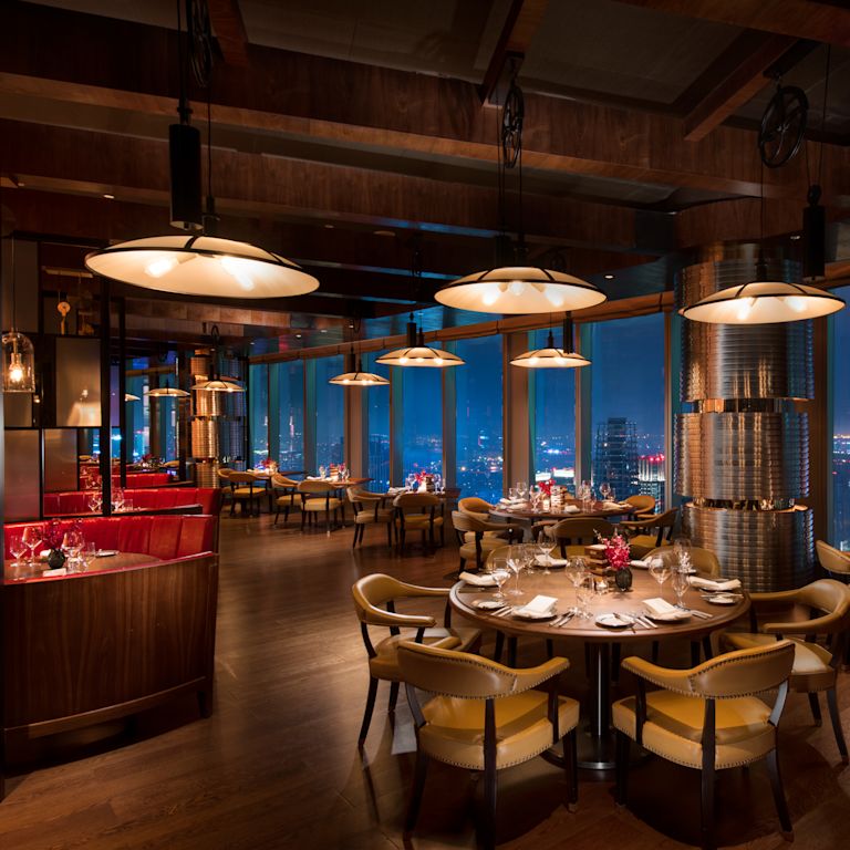Limited Edition Grill restaurant with dining tables, chairs, dining amenities, and floor-to-ceiling windows with city view at night