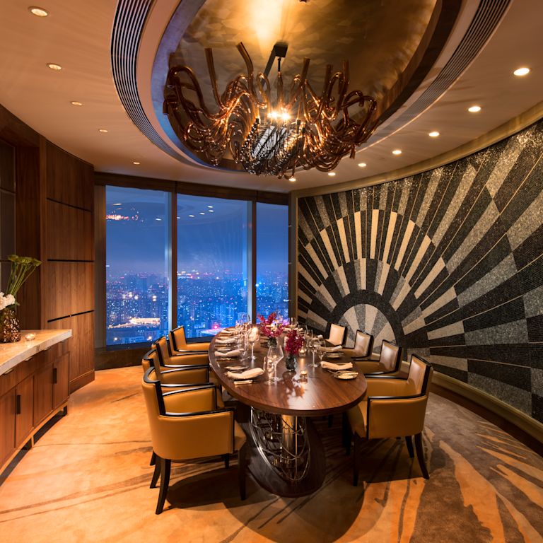 The Grill restaurant private dining room with large dining table, chairs, dining amenities, and floor-to-ceiling window with city view at night