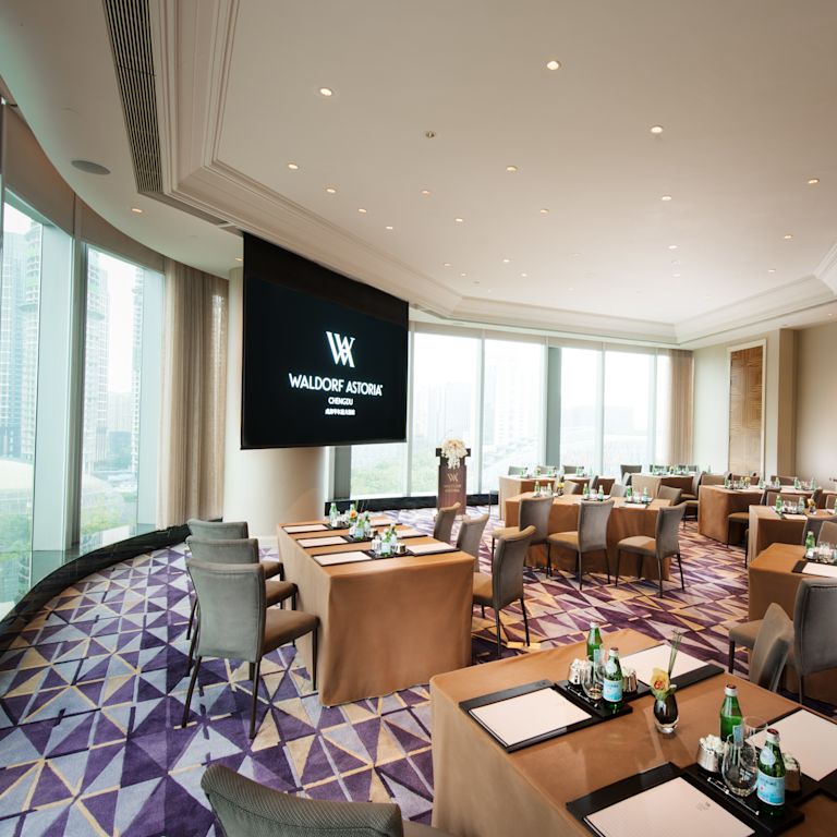 Times Square meeting room with tables, chairs, large presentation TV, and floor-to-ceiling windows with outdoor view