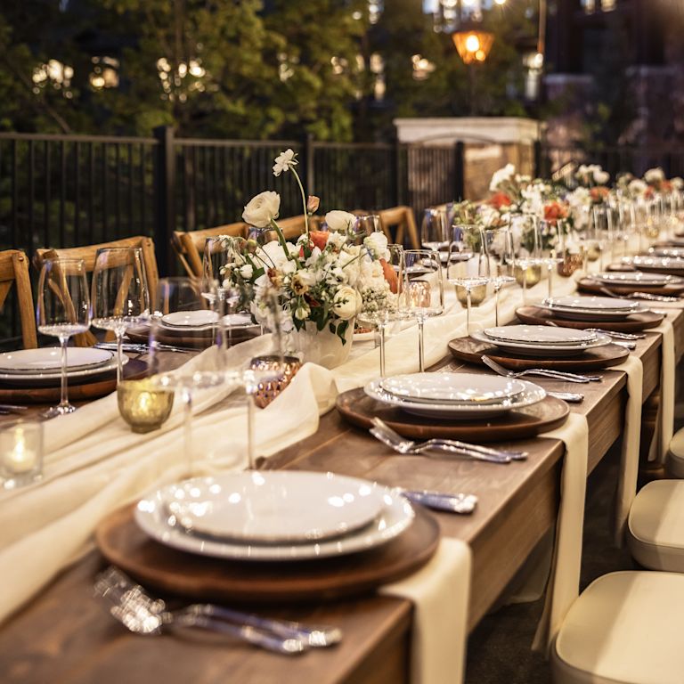 a Large Table Setup with Flowers for an Evening Event on a Terrace