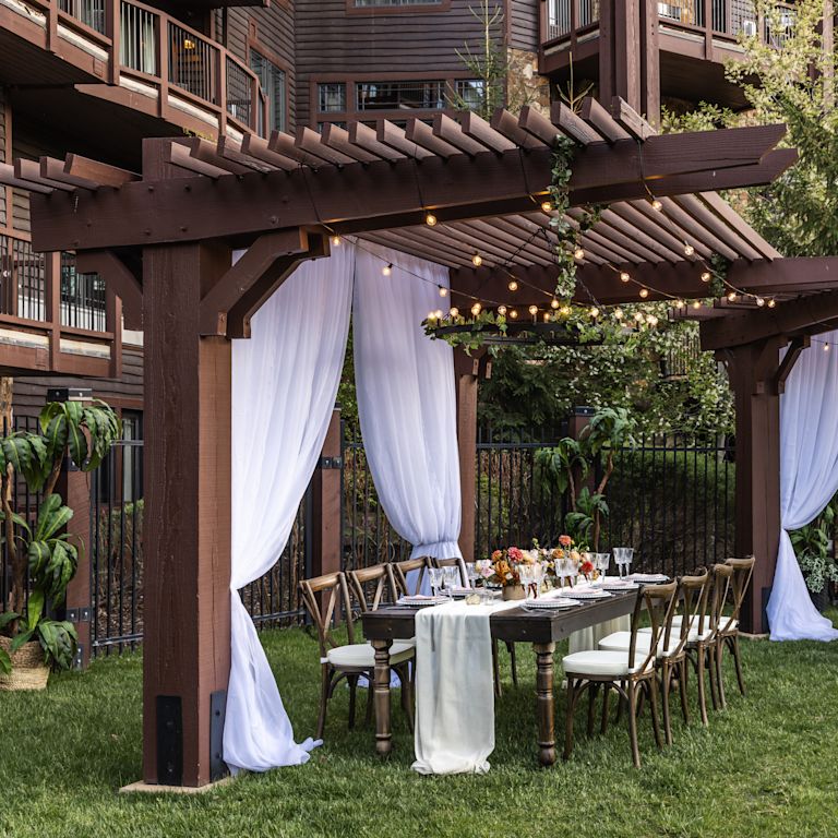 hotel courtyard, pergolas, dining tables with dinner ware, string lights
