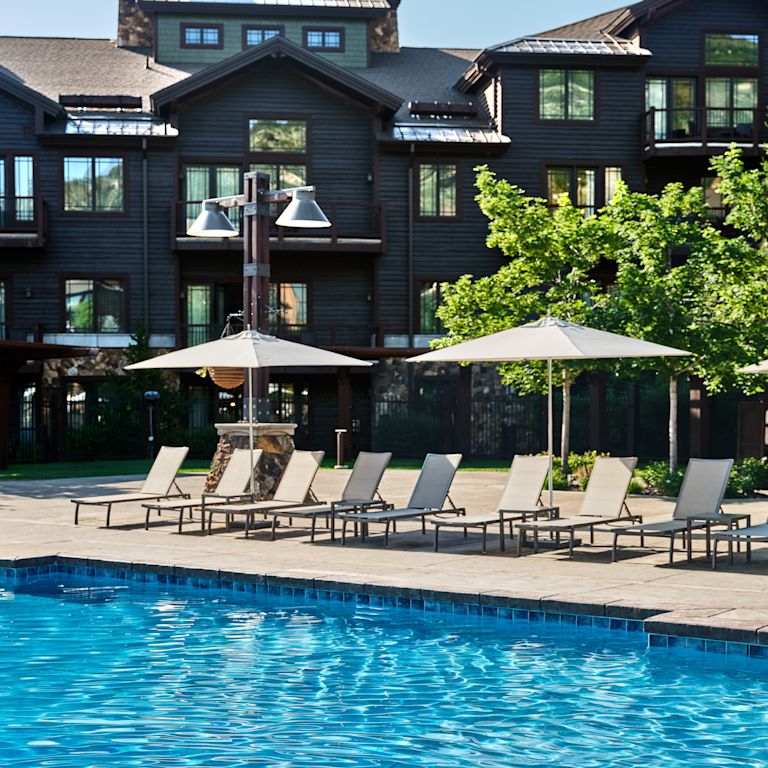 Outdoor Pool Area with Lounge Chairs under Umbrellas