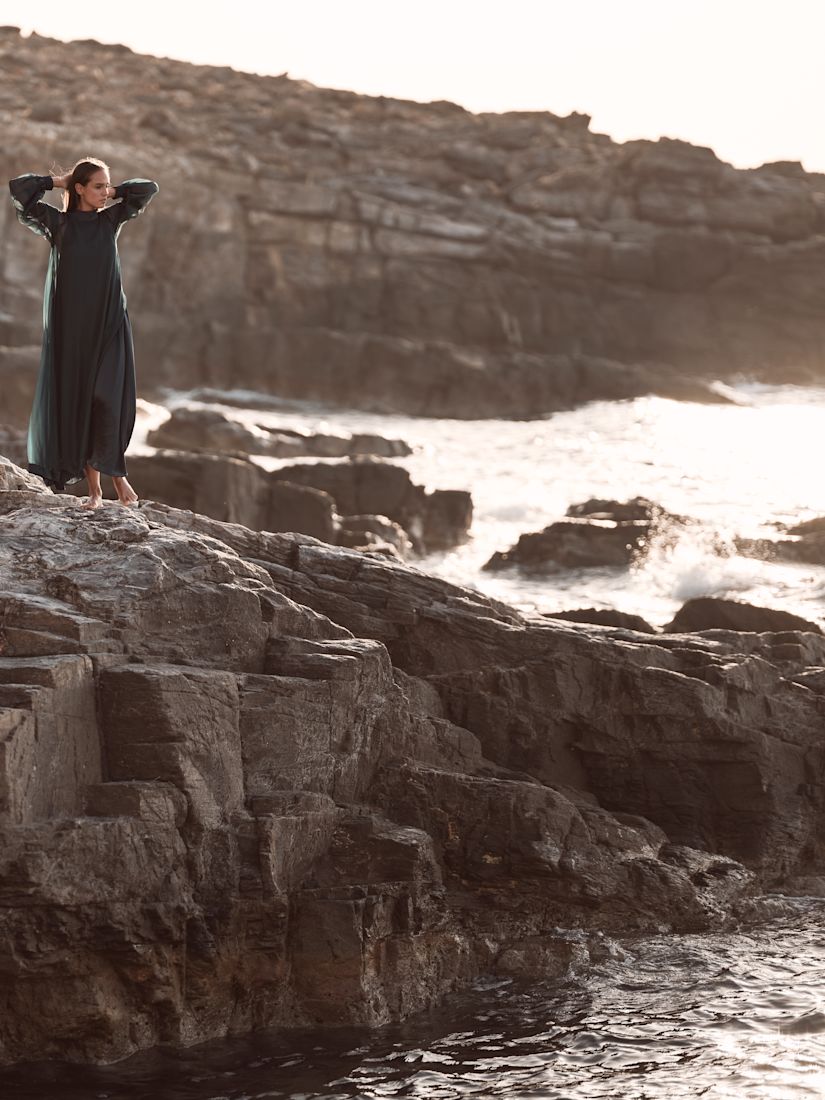 a Woman Standing on a Rock by the Sea