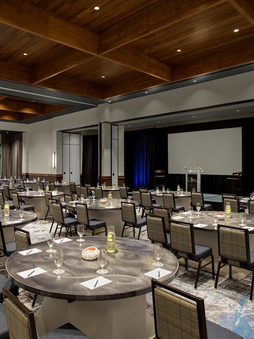 Cumberland Ballroom with round tables setup facing the front of the room and a large projector screen.-transition