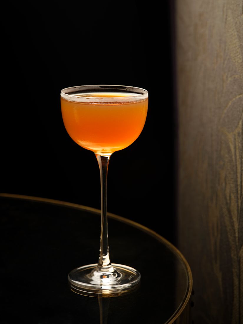 A coupe glass filled with an orange cocktail-previous-transition