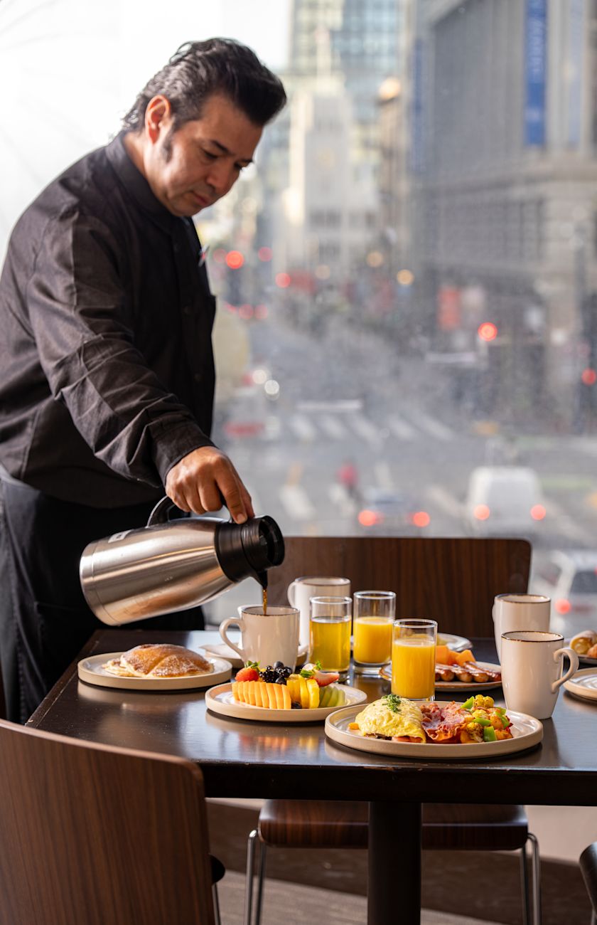 A waiter serving coffee on a table set for dining at Cable 55 restaurant