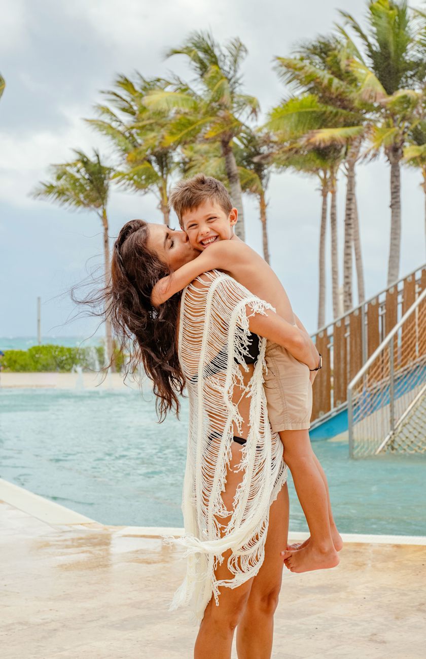 Young boy smiling at camera as his mum holds him in her arms
