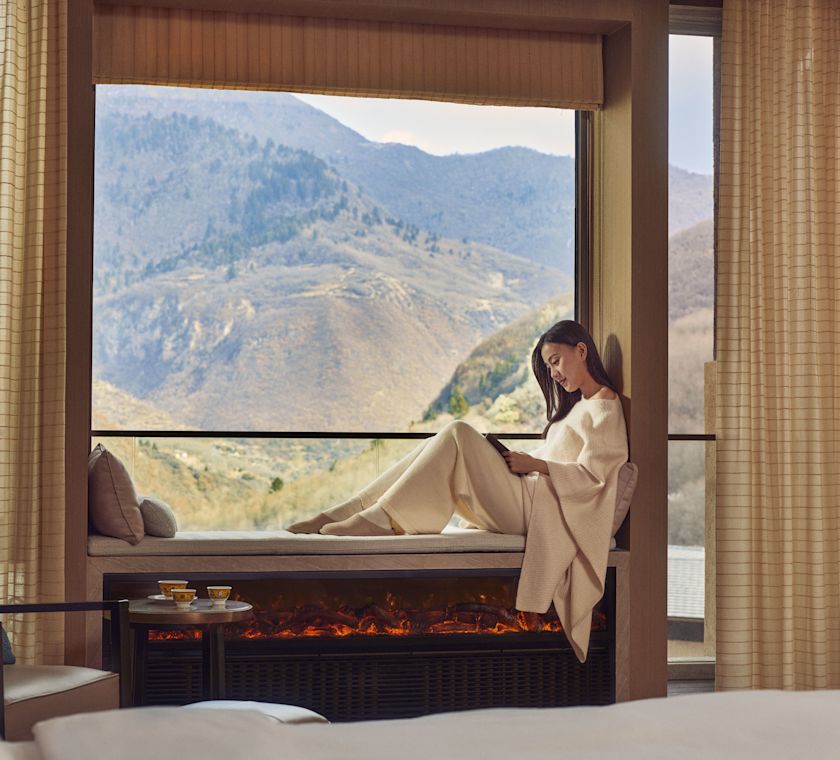 Wanita bersantai di ambang jendela dengan pemandangan gunung