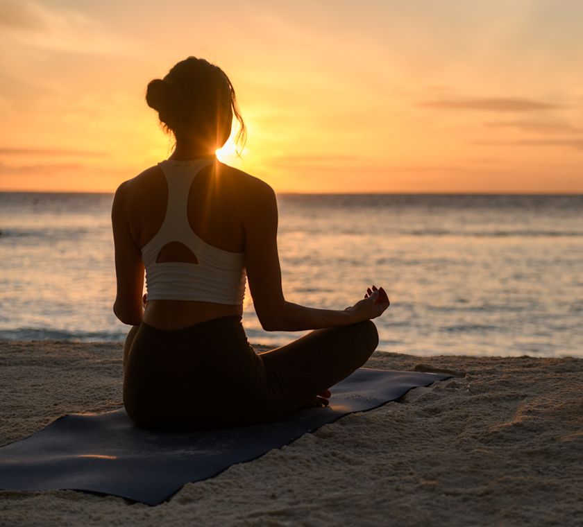 夕暮れのビーチでヨガを練習する女性