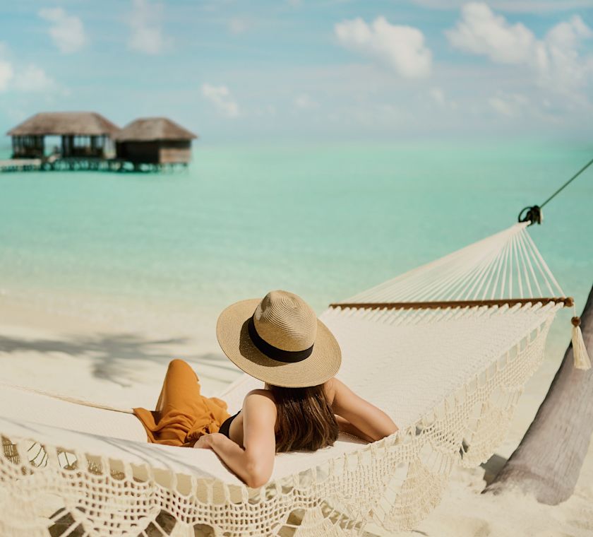 guests sitting in a hammock with a view of the water and guest suites