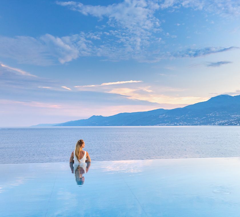 Woman in pool looking out over water