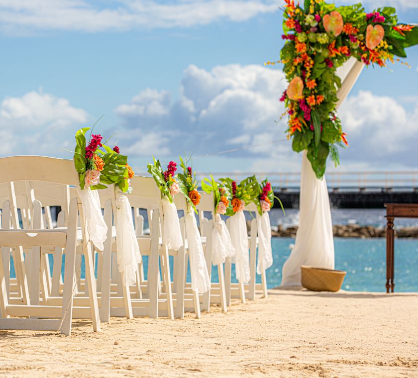 Cadeiras decoradas com flores para comemorar um casamento na praia
