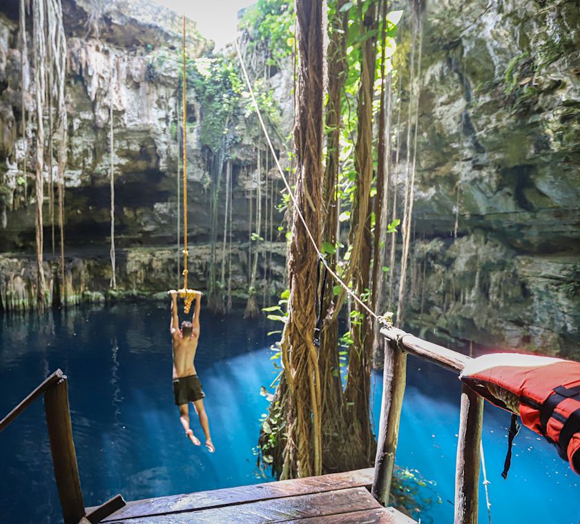 A person jumping into a lake from a rope swing