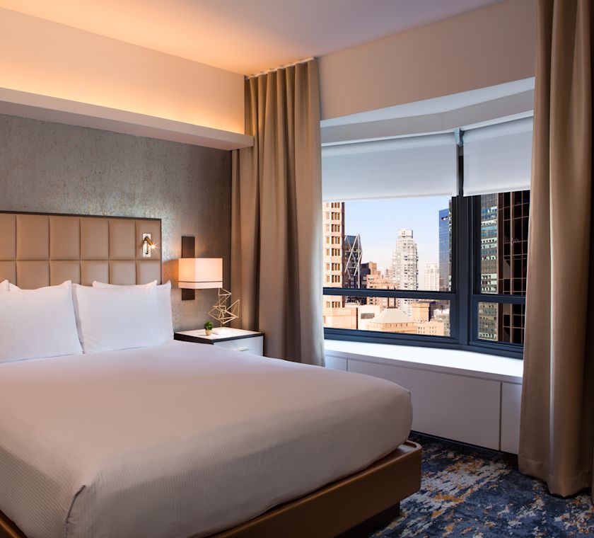 Suite bedroom with bed next to a window with views over the city