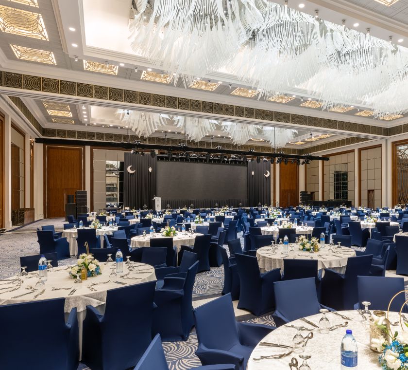 Ballroom setup with white covered round tables and blue covered chairs