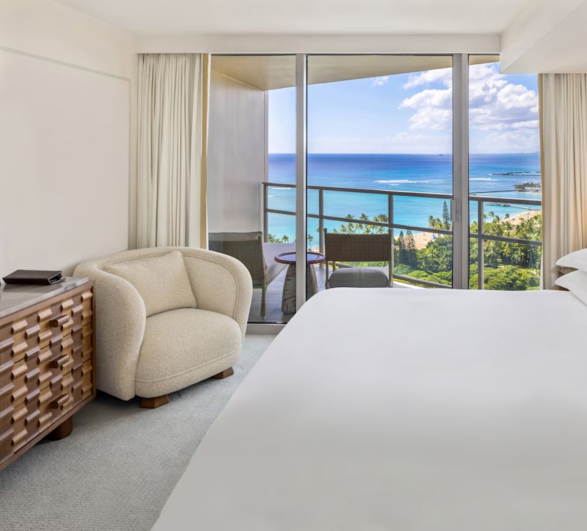 Large Bed and Soft Chair in a Suite with Ocean View from Balcony