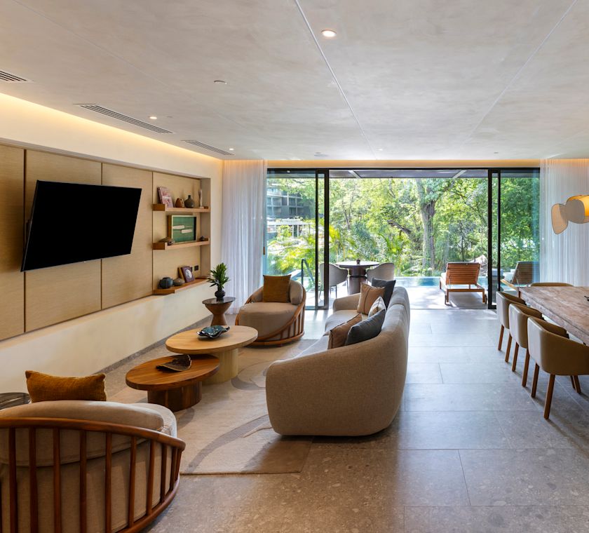 Espace salon, canapé, téléviseur, table de salle à manger, vue de la fenêtre du patio privé et de la piscine de la suite Pacifico
