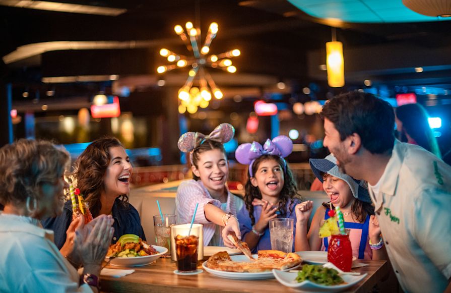Orang-orang yang bahagia duduk di meja dengan makanan dan kembang api di latar belakang transisi