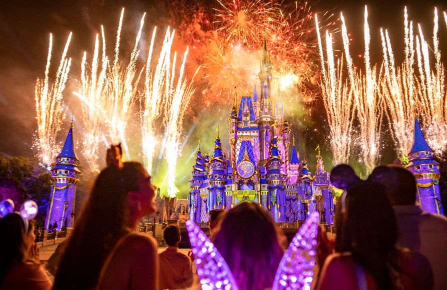 People standing in front of Disney castle with fireworks-transition