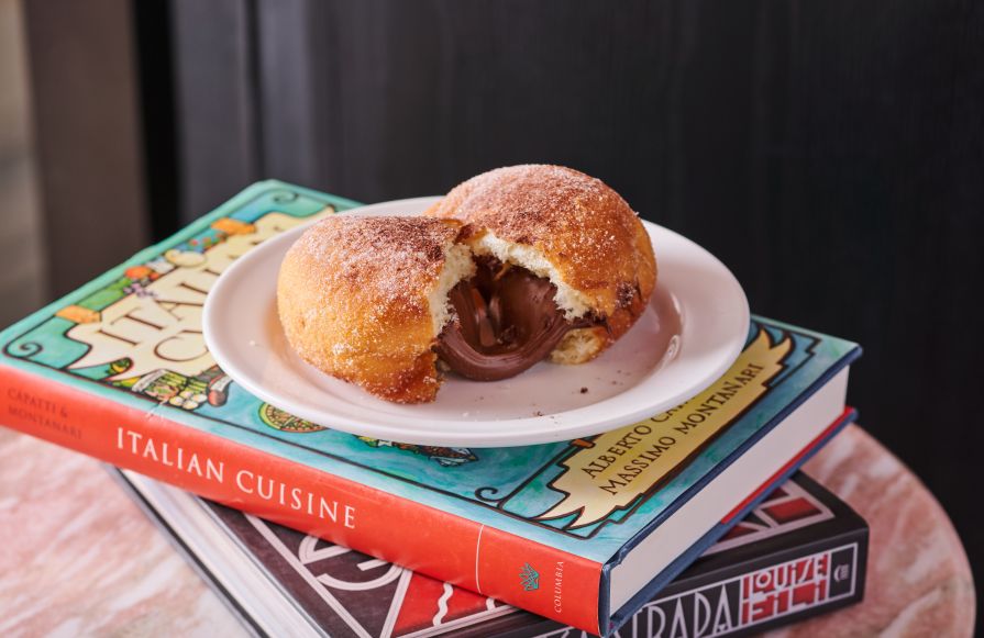 Chocolate Bombolone on a plate sitting on a couple of books