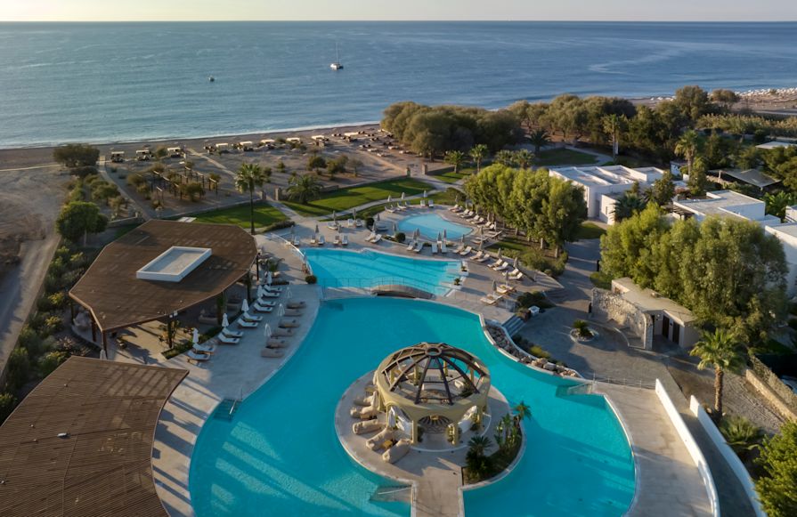 o zonă mare de piscină exterioară într-un hotel, lângă o zonă de tranziție pe plajă